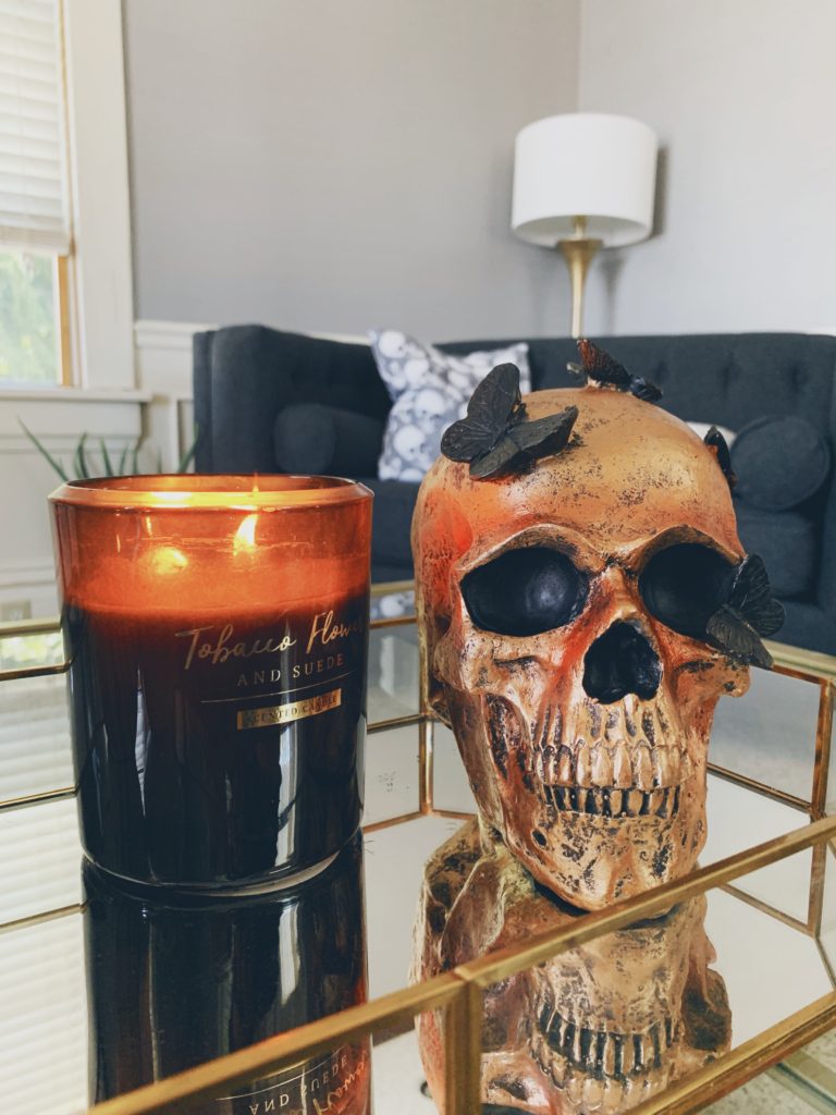 chic halloween decor, bronze skull sitting on gold coffee table tray next to a black candle