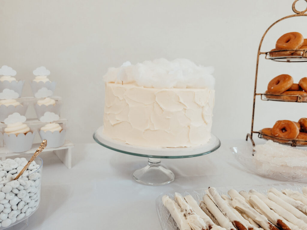 white cloud cake on a clear cake stand for a cloud themed baby shower