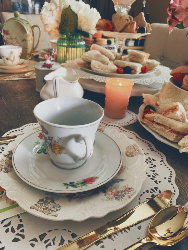 tea set with tea sandwiches and scones in the background of the image