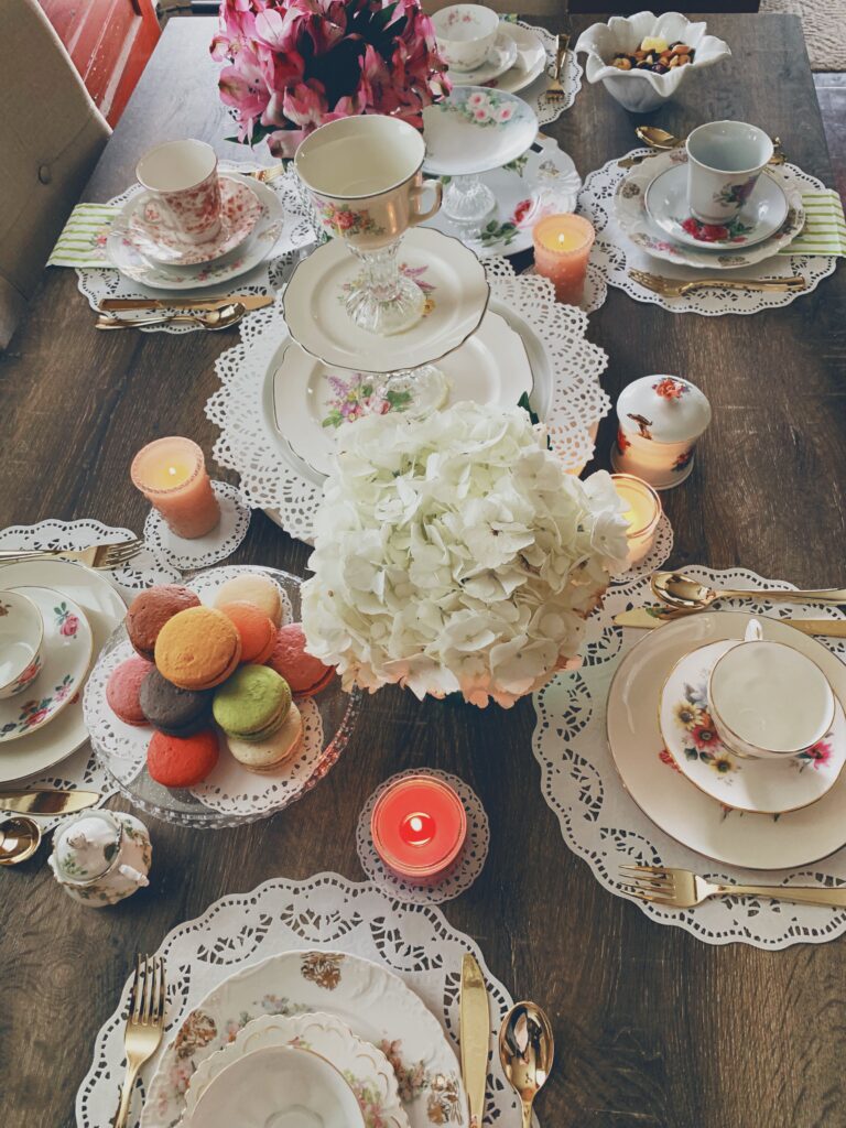 table spread with tea sets and macarons and flowers in vases for a Mother's Day brunch
