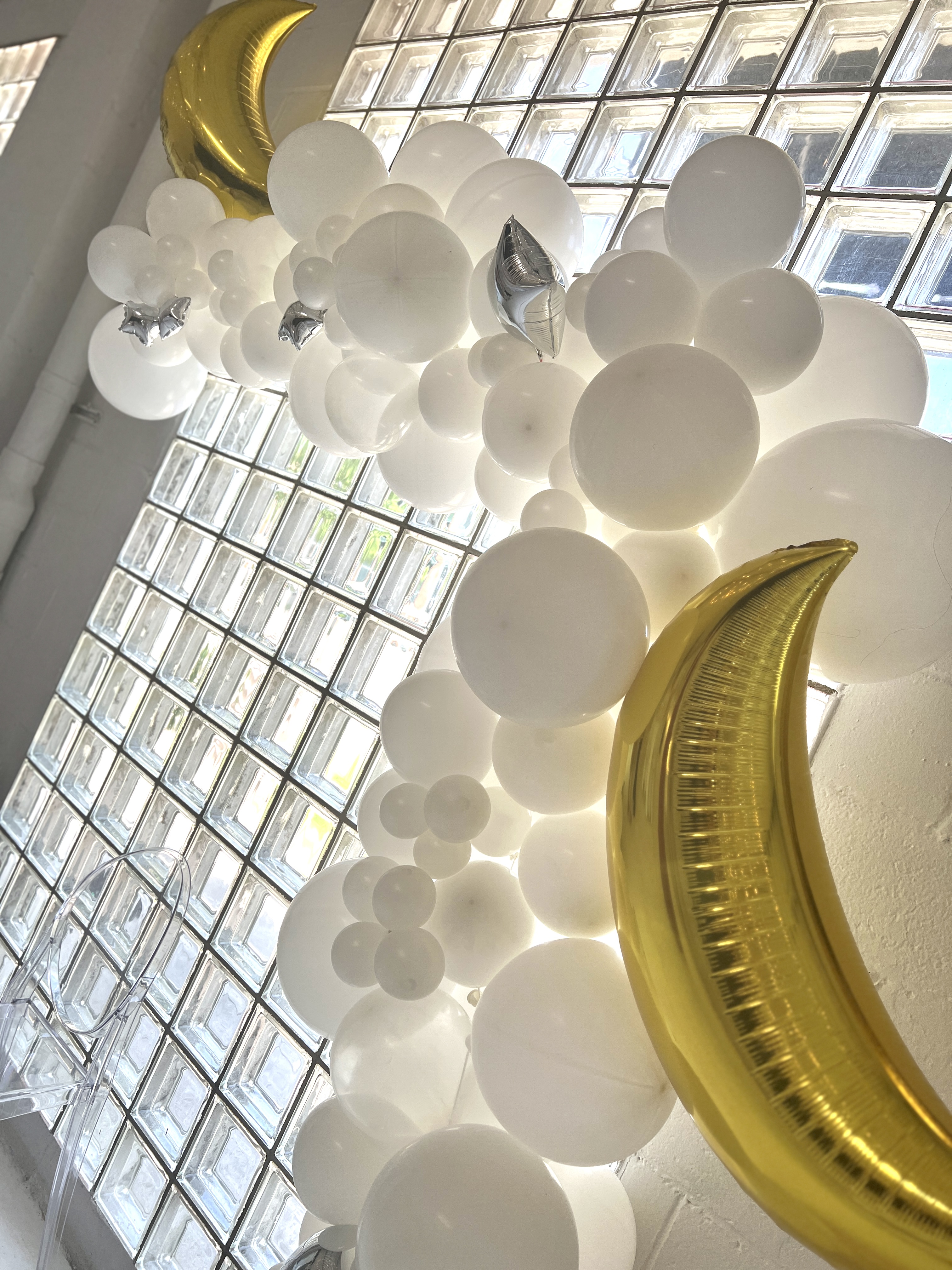 white balloon garland with gold moon balloons for a cloud themed baby shower