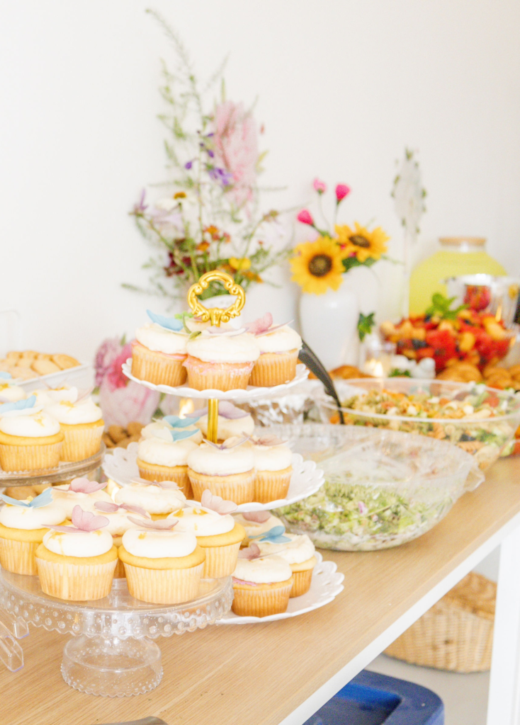 A beautiful food table display with lots of flowers and color for a garden party themed birthday