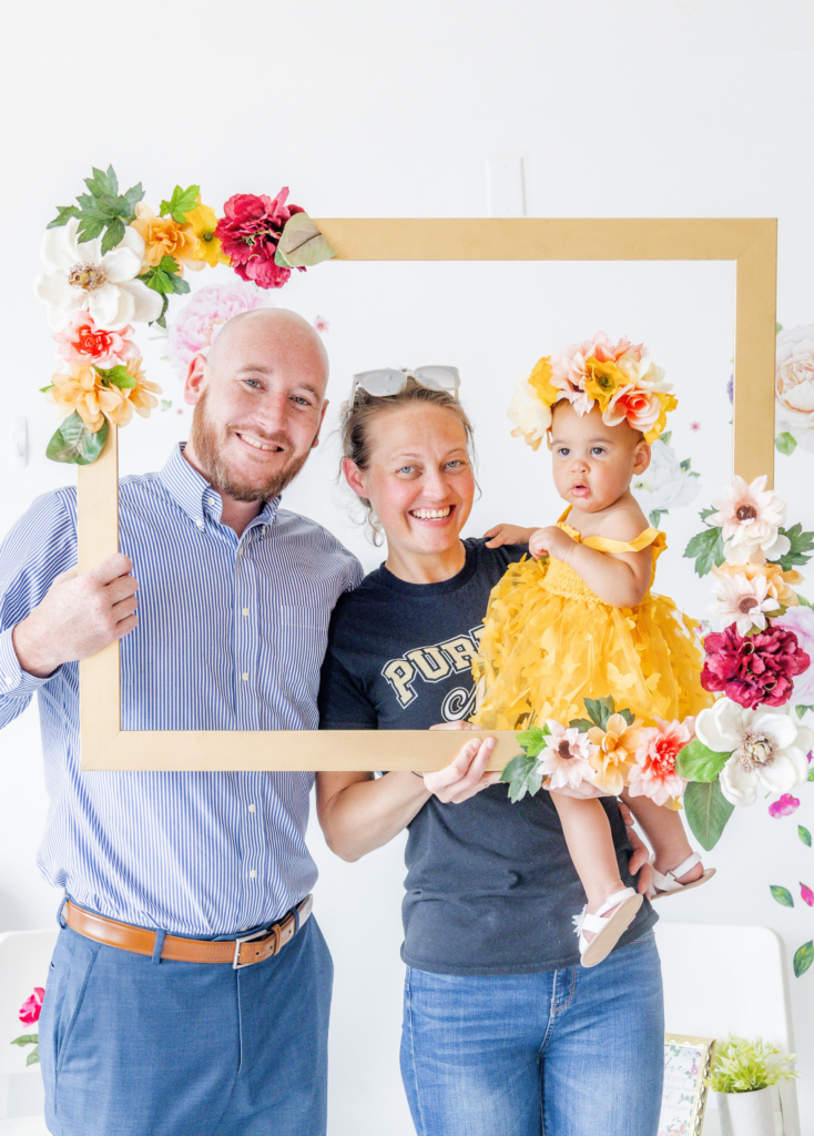 Gisele with Aunt Megan and Uncle Patrick posing along the selfie wall for her garden party themed birthday