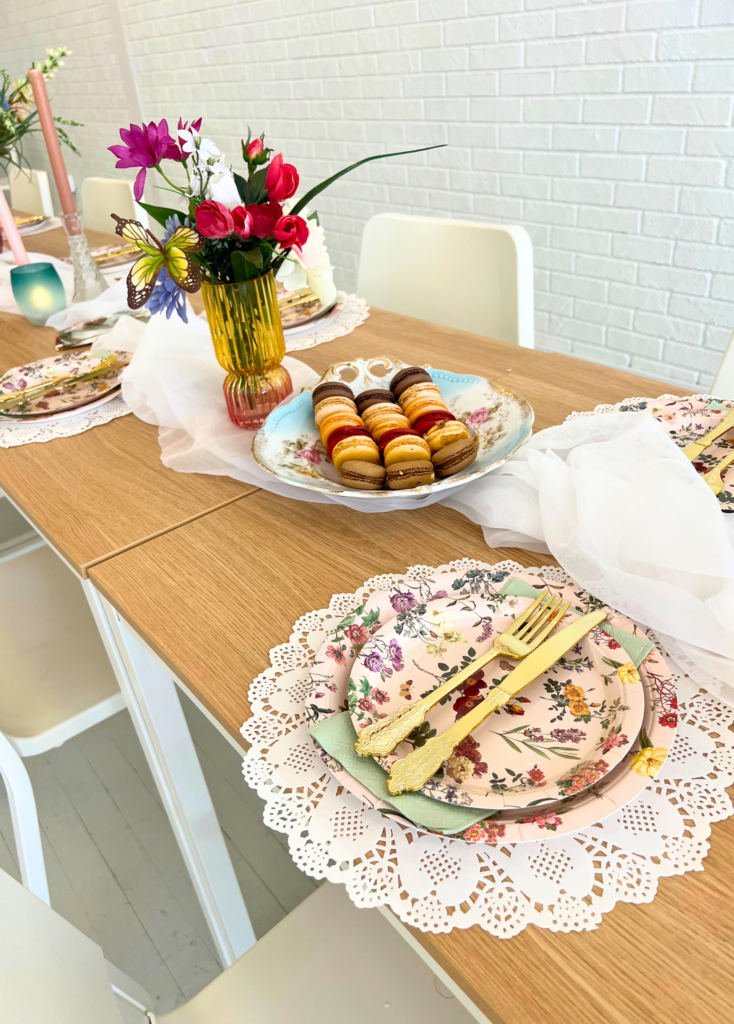 Place settings sitting on a table with a plate of macarons next to it for a garden party themed birthday