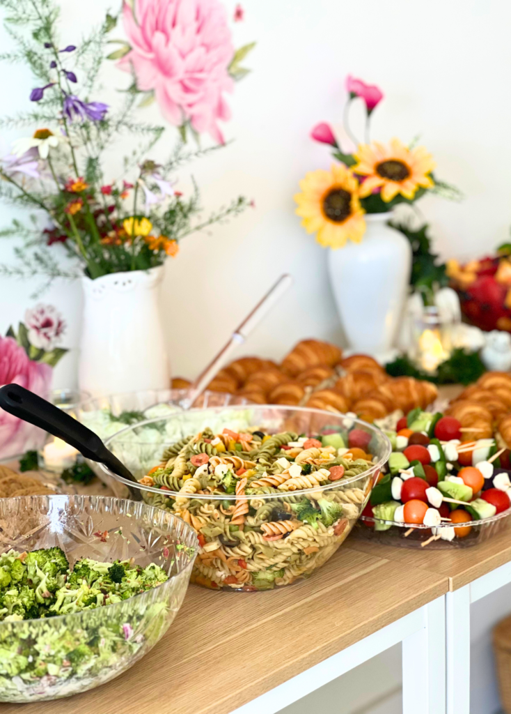 A beautiful food table display with lots of flowers and color for a garden party themed birthday