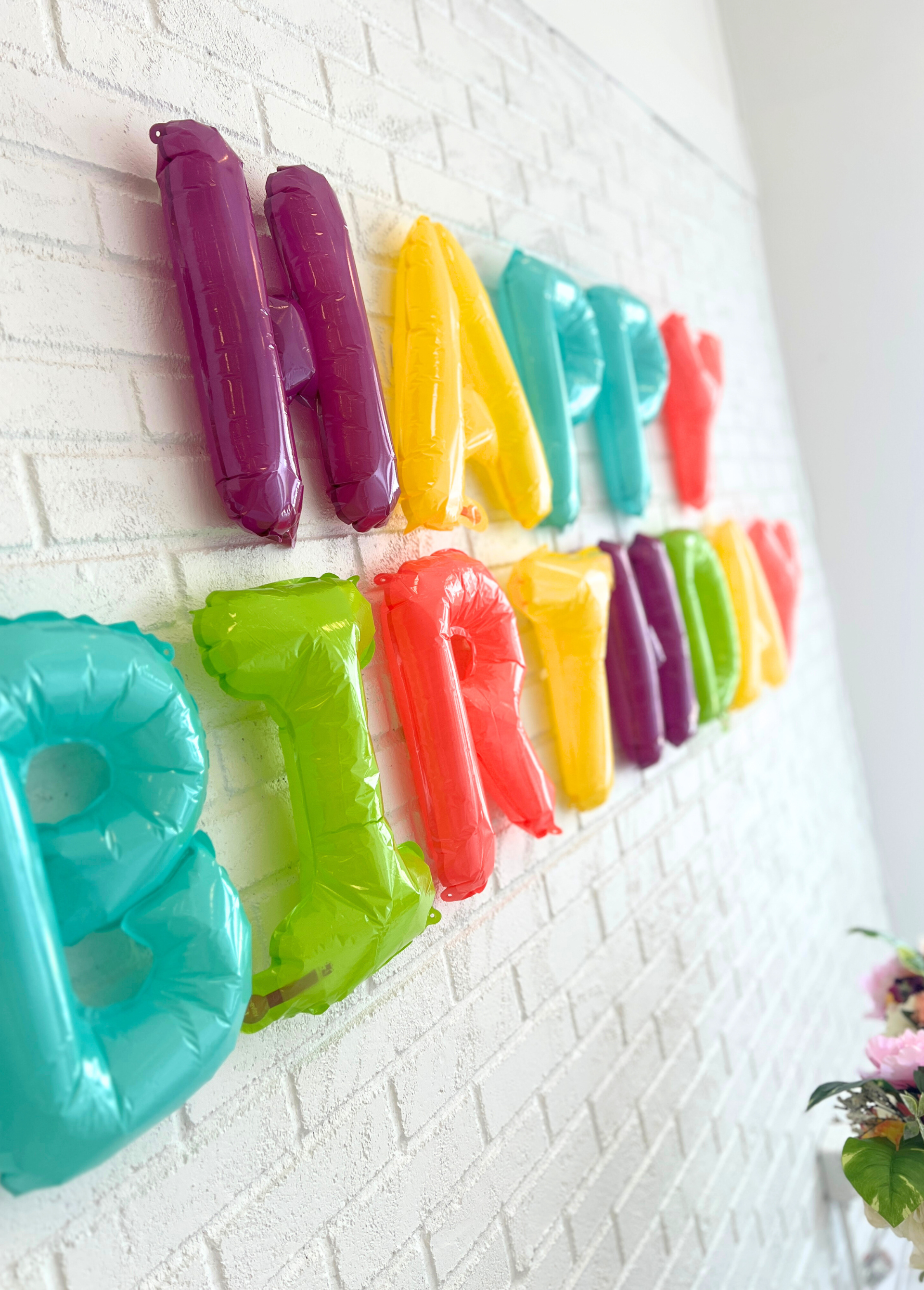 A wall of colorful happy birthday balloons at a Garden Party birthday