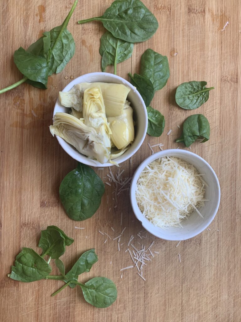 fresh spinach leaves, artichokes and shaved parmesan cheese ingredients needed to make an easy, spinach artichoke dip appetizer for a party or tailgate 