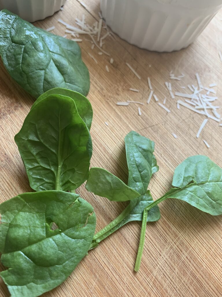 fresh spinach leaves are part of the ingredients needed to make an easy, spinach artichoke dip appetizer for a party 