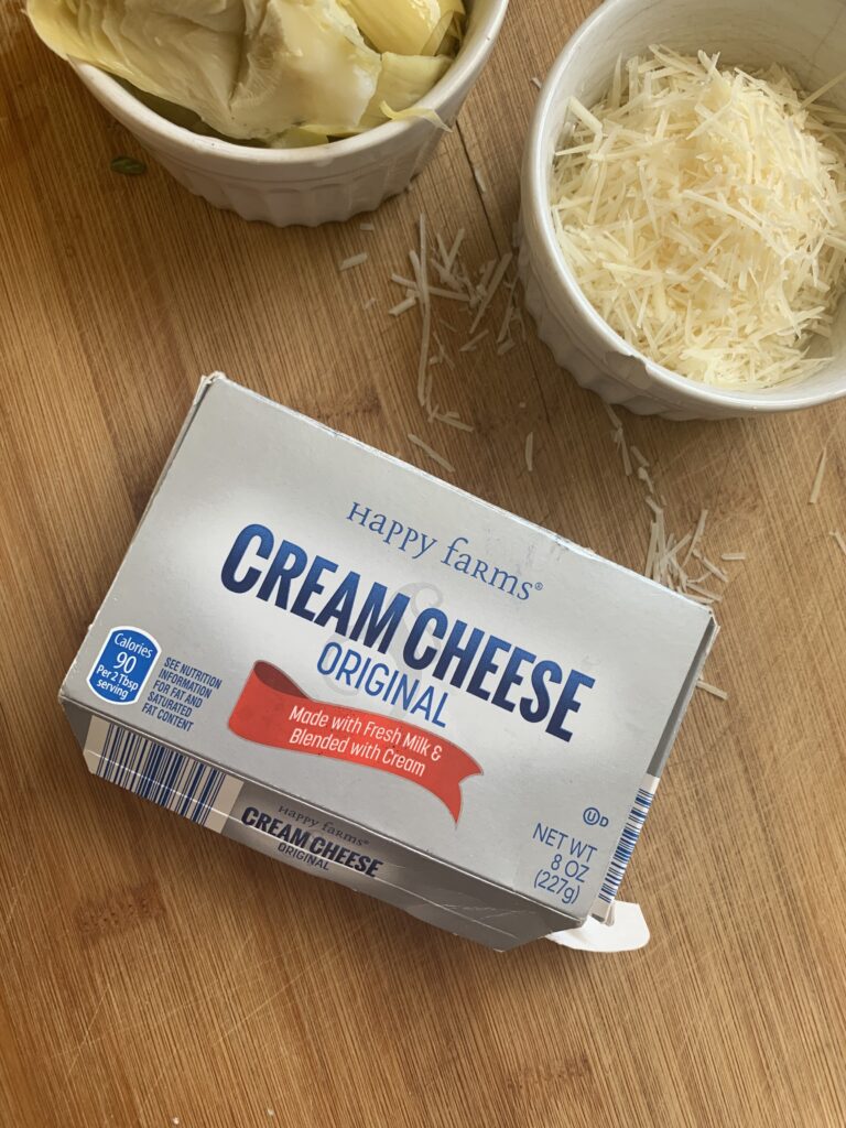 a packet of cream cheese as part of the ingredients needed for a recipe to make an easy spinach artichoke dip appetizer