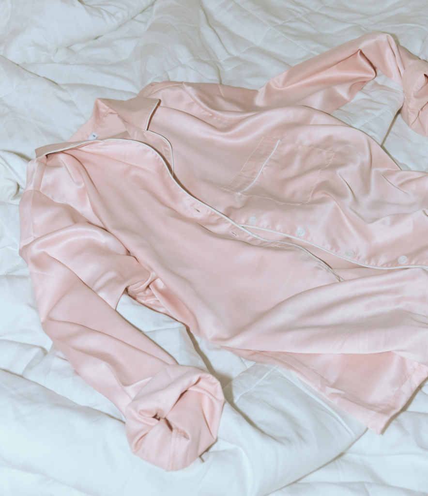 comfortable silky pjs laying on a white bed spread as attire for a festive cozy NYE celebration at home