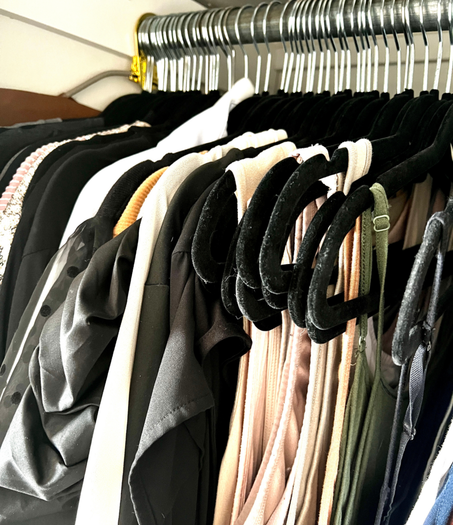 Neutral colored shirts hanging in closet for a blog post about mom hacks and style hacks