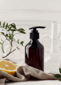 Glass soap bottle next to sliced lemon depicting realistic sustainable living practices