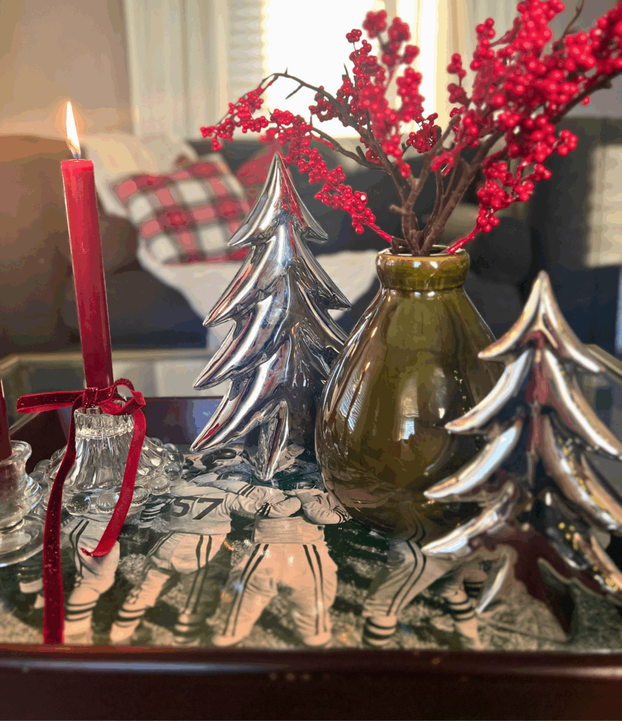Holly berry stems in green vase on coffee table tray with red candlesticks for a blog post about the Ralph Lauren Christmas trend.