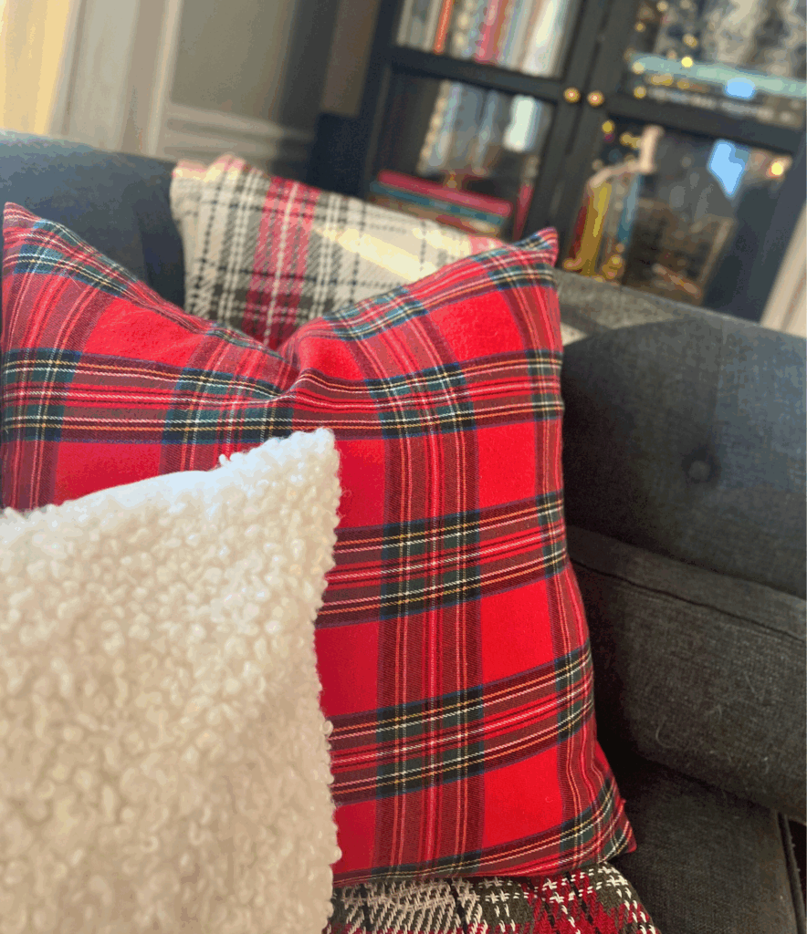 Red and white tartan printed pillows and blankets draped on a couch for a blog post about the Ralph Lauren Christmas trend.