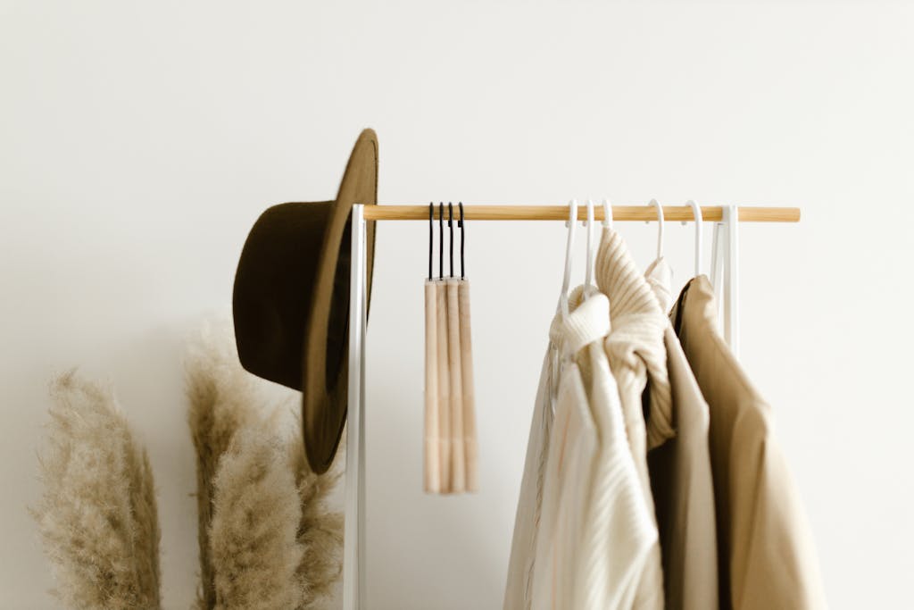 A minimalist clothing rack with neutral-toned garments and hat, creating a cozy home decor vibe.