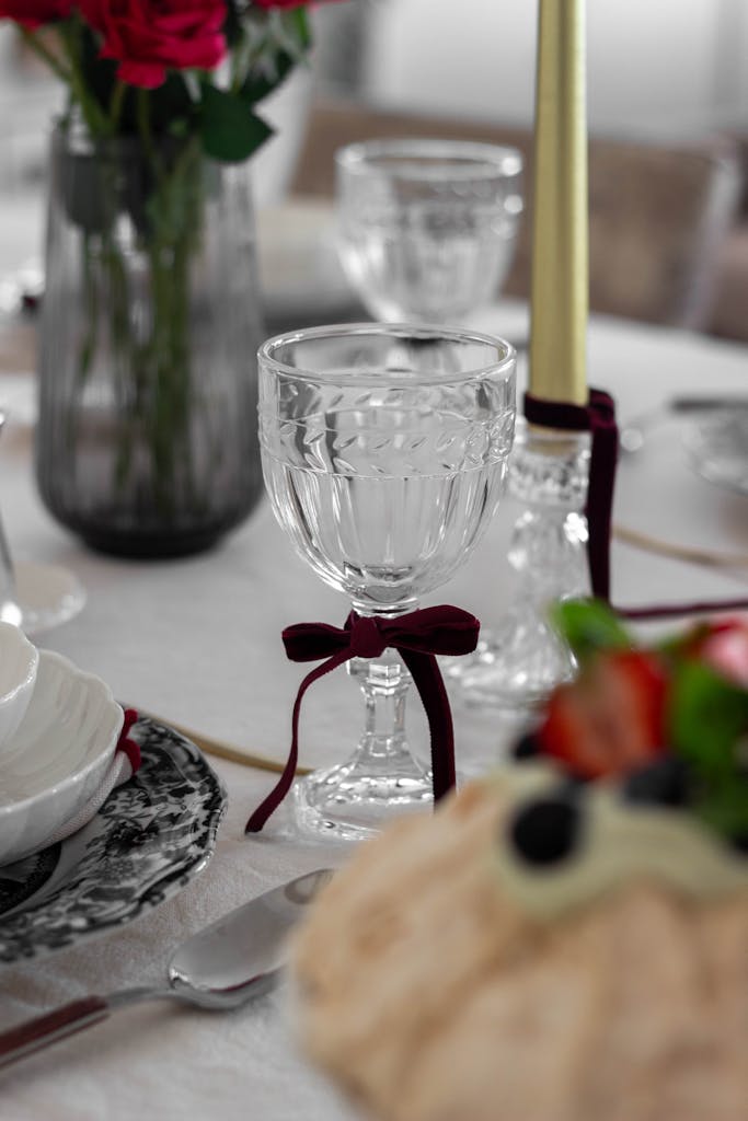 Chic table setup with crystal glasses, candles, and flowers, perfect for formal gatherings.