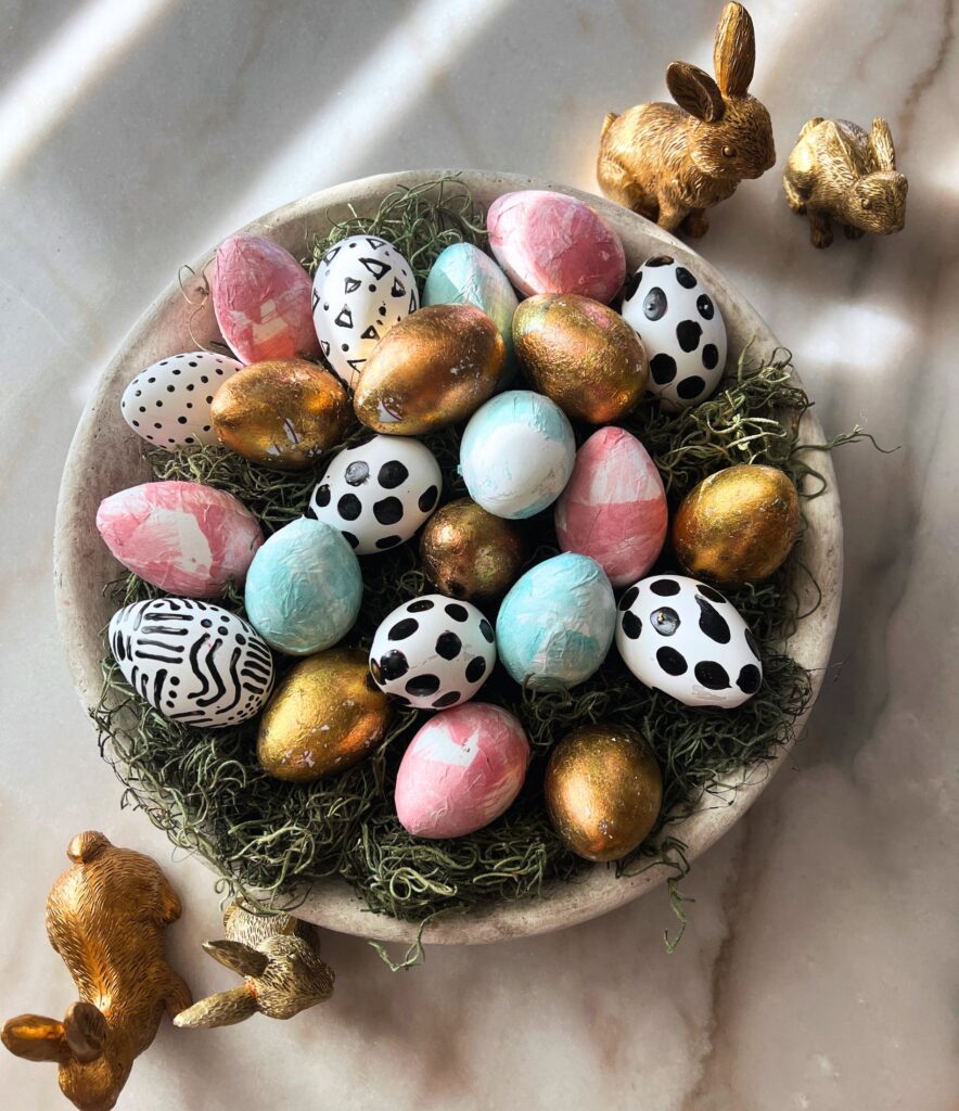 simple spring decor detail of pastel Easter eggs in a travertine bowl on a clean marble dining table